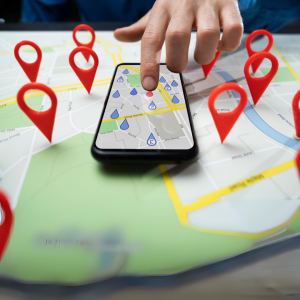 A hand points to Local SEO results on a smartphone, which is sitting on a map with location pins.