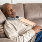 A man at rest without guilt, having a nap with a book on his chest.