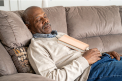 A man at rest without guilt, having a nap with a book on his chest.
